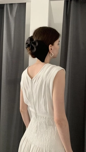 Detail of elegant black satin bow hair clip styled on a low bun with a white dress