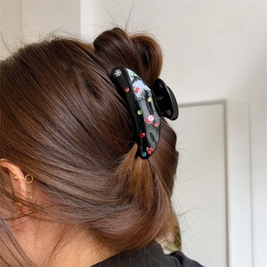 Dettaglio della pinza per capelli nera con statuetta di Babbo Natale e strass festivi