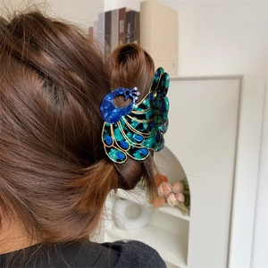 Detail view of peacock hair claw clip with blue and green marble texture on hair