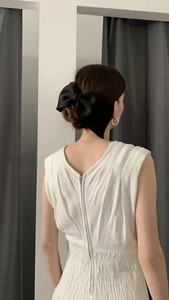 Elegant large black satin bow hair clip styled on a low bun for a classic French vintage look