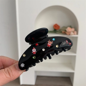 Dettaglio della molletta in acetato con strass colorati e decorazioni natalizie