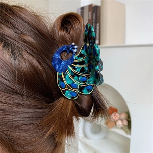 Detail of peacock shaped hair claw clip in blue and green marble acetate on brown hair
