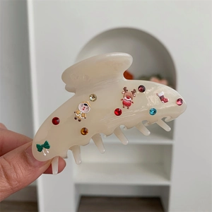 Dettaglio della molletta per capelli crema con ciondoli natalizi e strass colorati