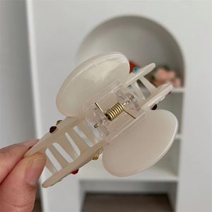 Dettaglio molletta per capelli in acetato crema con strass colorati e molla dorata