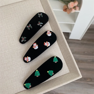Three Christmas hair clips with velvet texture featuring tree, snowman, and green bow