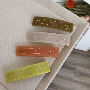 Détail de quatre pinces à cheveux en acétate coloré avec strass brillants en plateau