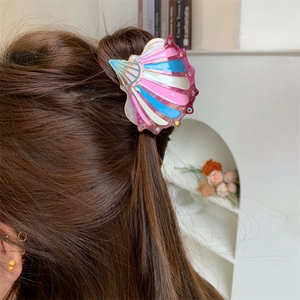 Detail of shell-shaped acetate hair claw with rhinestones on long brown hair