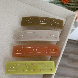 Détail de pinces à cheveux en acétate avec strass dans des tons olive et ambre doux
