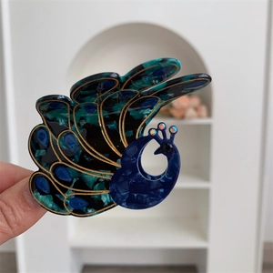 Detail of peacock hair claw clip with acetate marble texture and rhinestone accents