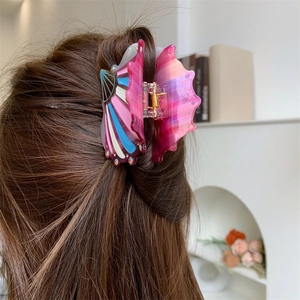 Detail showing shell-style acetate hair claw clip with colorful rhinestones and gold spring