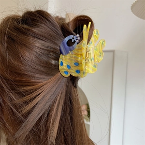 Detailed peacock-shaped hair claw clip in yellow and blue marbled acetate on long hair