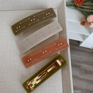 Vue détaillée de barrettes rectangulaires en acétate avec strass et pinces dorées