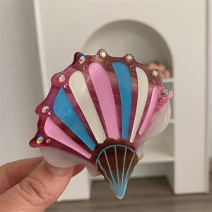 Close-up of shell-shaped acetate hair claw with rhinestones and colorful stripes