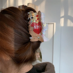 Detail of holographic acrylic bear hair claw clip holding a heart on a bun hairstyle