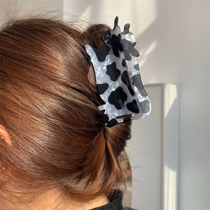 Molla per capelli in acrilico con stampa mucca bianca e nera indossata lateralmente