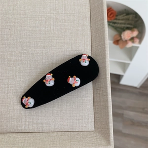 Detail view of a Christmas snowman hair clip with four resin charms on a black fabric base