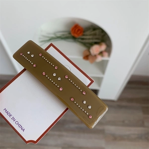 Gros plan d'une pince à cheveux rectangulaire marron avec des strass roses et blancs