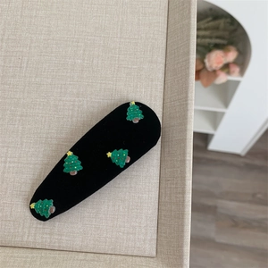 Detail showing four green flocked Christmas tree charms on a black velvet hair clip