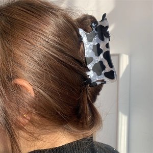 Grande molletta per capelli con stampa mucca in acrilico indossata su capelli raccolti