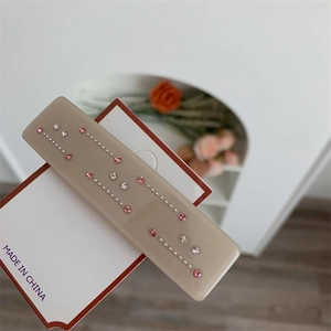 Détail d'une pince à cheveux en résine kaki avec strass roses sur sa carte