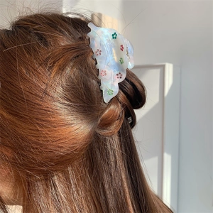 Détail d'une pince à cheveux translucide nacrée avec des motifs floraux en strass colorés