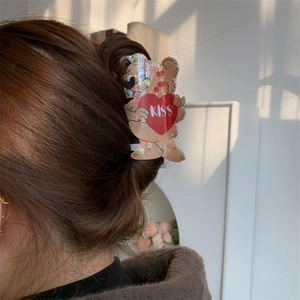 Detail of cute bear hair claw with kiss heart design holding a brown hair bun