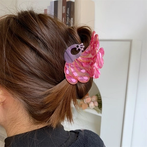 Detail view of peacock hair claw clip with pink and purple marble texture on brown hair