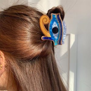 Detail of printed evil eye hair claw clip showing glossy acrylic texture in hair