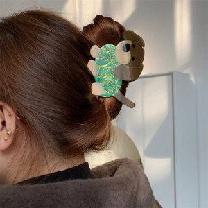 Détail d'une pince à cheveux en forme de chien en acétate portée sur une chevelure