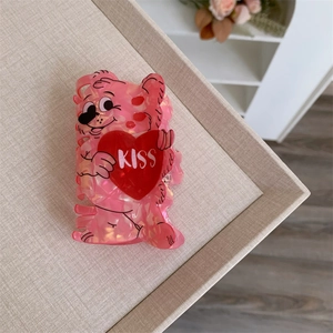 Macro detail of a pink glittery bear claw clip with a red heart and KISS lettering