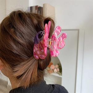 Detail showing marble texture peacock-shaped hair claw clip on model's hair