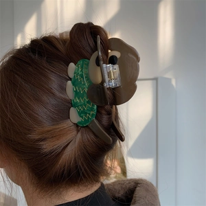 Gros plan d'une pince à cheveux en acétate en forme de chien portée sur cheveux châtains