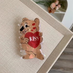 Close-up of a brown acetate bear hair claw clip with a red heart and KISS text