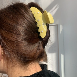 Pinza per capelli gialla in acetato con perle finte indossata su lunghi capelli castani