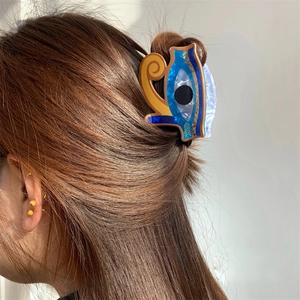 Detail showing an acrylic Egyptian Horus eye hair claw clip on a woman's half-up hairstyle