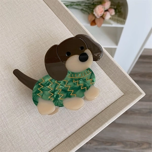 Détail d'une pince à cheveux teckel en acétate avec un motif de pull vert créatif