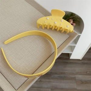 Dettaglio del cerchietto giallo con strass floreali e un fermaglio per capelli con perle