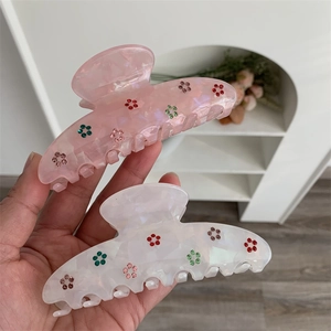 Détails de motifs floraux en strass sur des pinces à cheveux rose et blanc