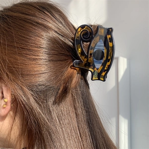 Detail of acrylic hair claw clip with evil eye design on model's hair for styling