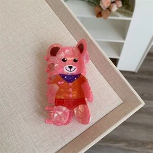 Detail view of pink bear hair claw clip with marble texture and purple polka dot scarf
