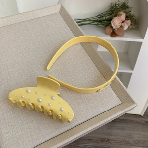 Dettaglio del cerchietto giallo con strass floreali e grande fermaglio per capelli in perle