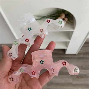 Détail de pinces à cheveux ondulées nacrées avec des motifs de fleurs en strass colorés