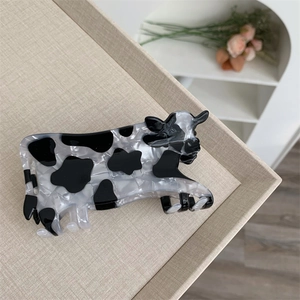 Dettaglio della grande pinza per capelli in acrilico con stampa animalier mucca bianca e nera
