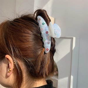 Pince à cheveux fleurie en acrylique blanc ornée de cristaux sur une coiffure arrière