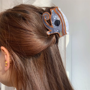 Detail view of acetate hair claw clip with purple marble texture on long hair