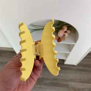 Dettaglio di un fermaglio per capelli a farfalla gialla con denti a incastro e molla