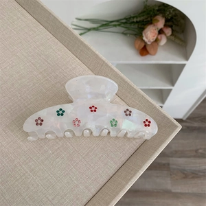 Détail de la pince à cheveux en résine marbrée blanche avec fleurs en strass colorés