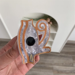 Detail view of acrylic evil eye kettle hair claw with white pearl texture and orange edges