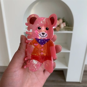 Close-up of cute pink bear hair claw clip with colorful clothes and glittery finish