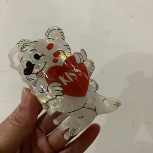 Detail view of a pearlescent bear hair claw clip featuring a red heart with KISS text